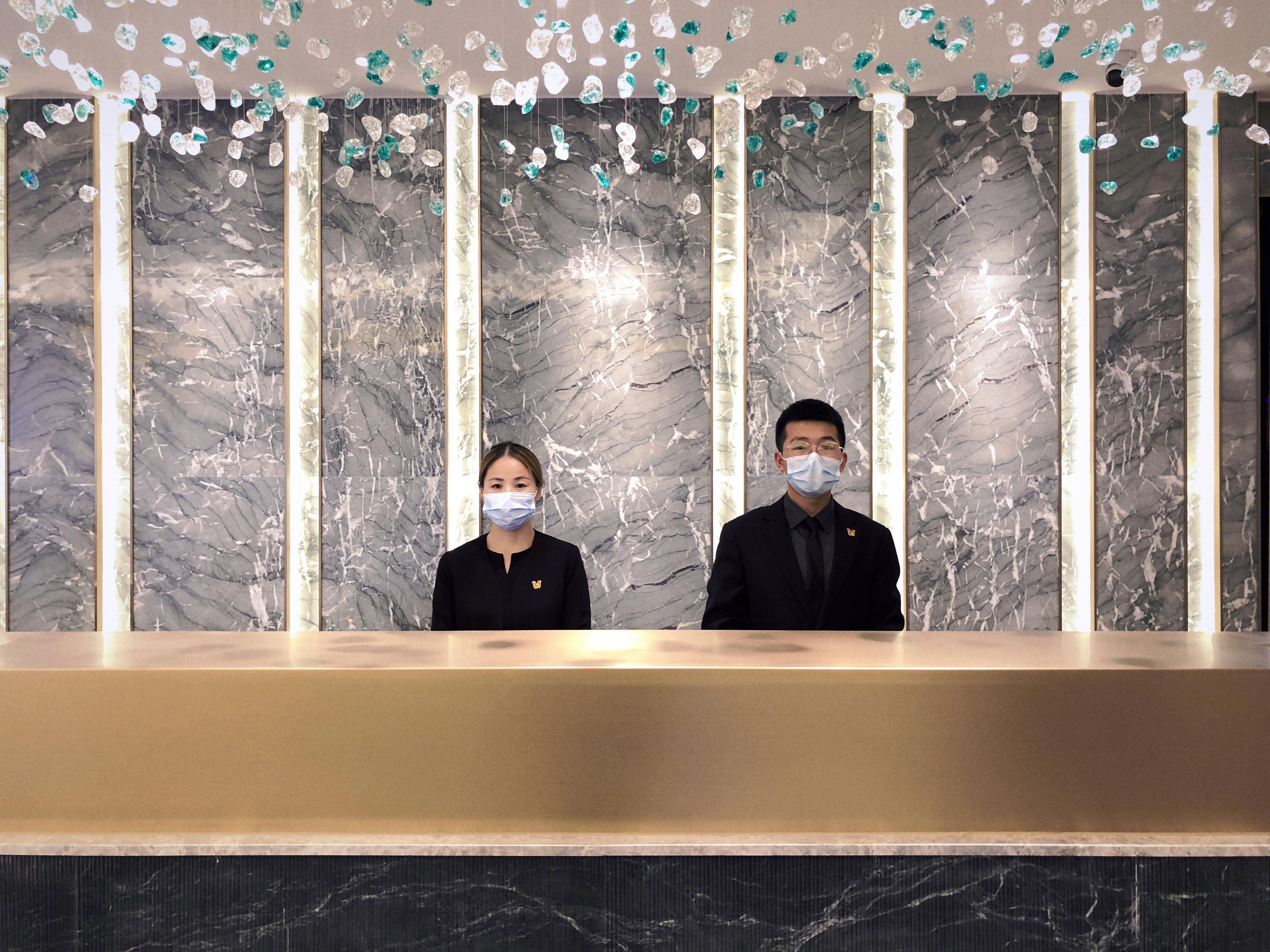 A reception desk with marble walls and hanging crystal decorations.