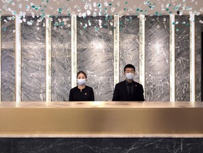 Un mostrador de recepción con paredes de mármol y decoraciones de cristal colgantes.