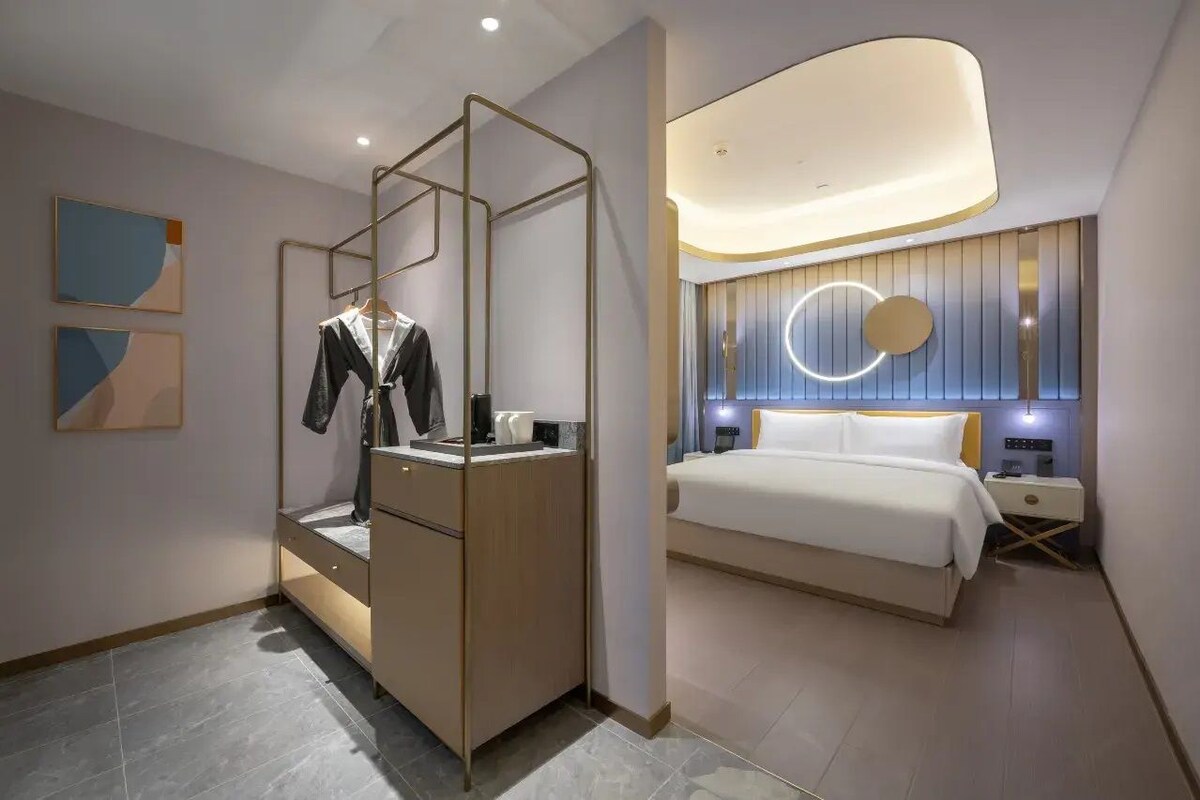 Una habitación de hotel moderna con cama, mesita de noche y armario con espejo.