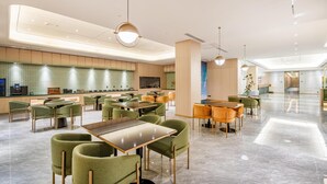 En rummelig hotellobby med flere siddeområder, en receptionsdisk og et moderne design.
