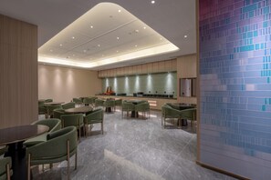 Un interior moderno con zona de cocina, sillas tapizadas en verde y salpicadero de azulejos.