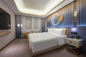 Een moderne hotelkamer met een groot bed, nachtkastje en een tv aan de muur.