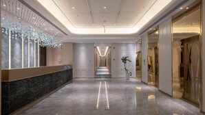 Et hotel med en lobby, en receptionsdisk i marmor, en lang gang og et moderne loftdesign.