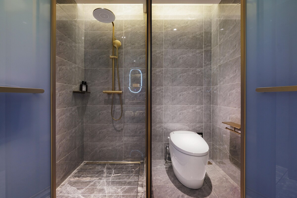 Un baño moderno con ducha de vidrio, inodoro y estante.