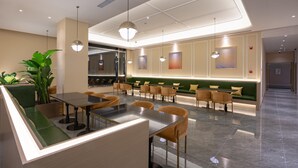 Un restaurante moderno con una zona de asientos en cabinas verdes, una barra y lámparas colgantes.