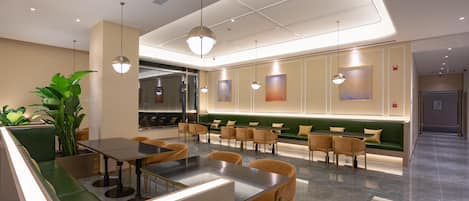 A modern restaurant with a green booth seating area, a bar, and pendant lighting.