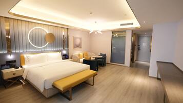 A modern hotel room with a bed, bedside table, lamp, and a bench.