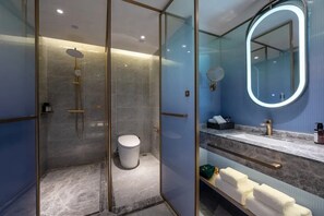 Une salle de bain moderne avec une douche à parois de verre, un meuble-lavabo doté d’un plan de travail en marbre, un grand miroir et des toilettes.