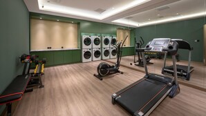 Un gimnasio con cinta de correr, elíptica y máquinas de pesas.