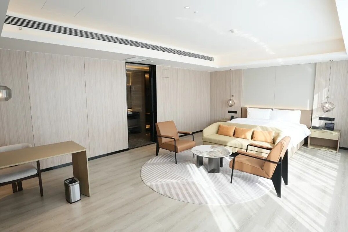 Una habitación de hotel moderna con cama, sofá, mesa de centro y escritorio.