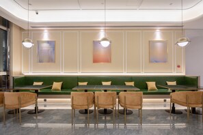 Un restaurante moderno con asientos acolchados verdes, una mesa larga e iluminación colgante.