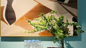 Ein Zimmer mit einem großen, abstrakten Gemälde, einem Wasserspender und einem kleinen Topfpflanzen.