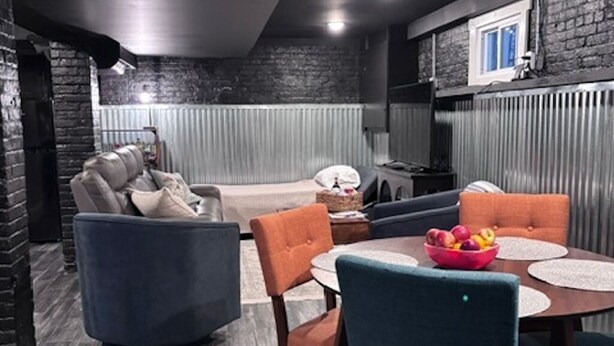 A modern interior with a dark ceiling, a stone wall, a fireplace, and a dining area with a round table and chairs.