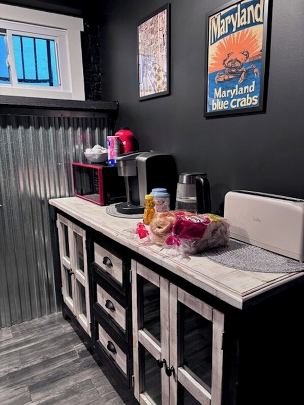 Una cocina compacta con encimera blanca, cafetera y una bolsa de alimentos.