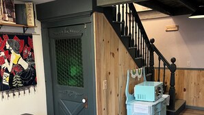 A room with a wooden door, a staircase with black balusters, and a blue dresser.