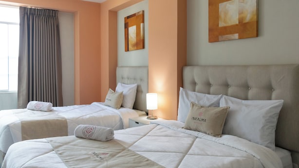 A hotel room with two beds, each with a headboard, a bedside table, and a lamp. - Inkalma sede Don Bosco (Arequipa)