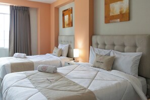 A hotel room with two beds, each with a headboard, a bedside table, and a lamp. - Inkalma sede Don Bosco (Arequipa)