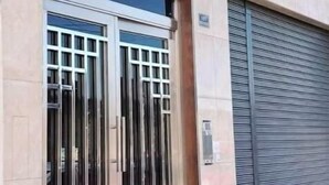 A building with a large metal gate and a closed roller shutter. Flags of various countries are displayed above the gate. - Inkalma sede Don Bosco (Arequipa)