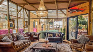 A spacious, well-lit room with leather sofas, a wooden coffee table, and a large window offering views of the outside.