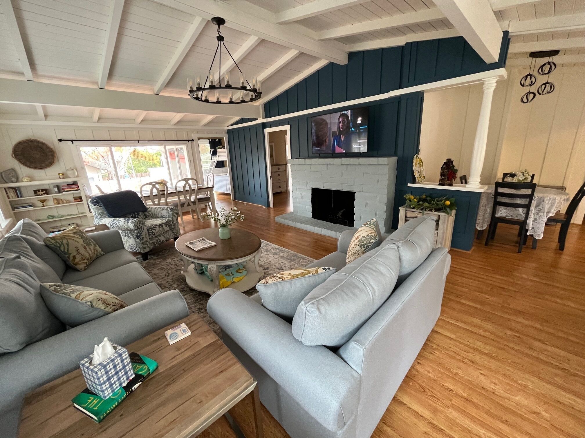 A spacious living room with a fireplace, a dining area, and a kitchen in the background.