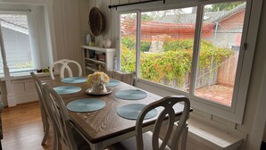 A dining area with a wooden table, white chairs, and a vase of flowers.