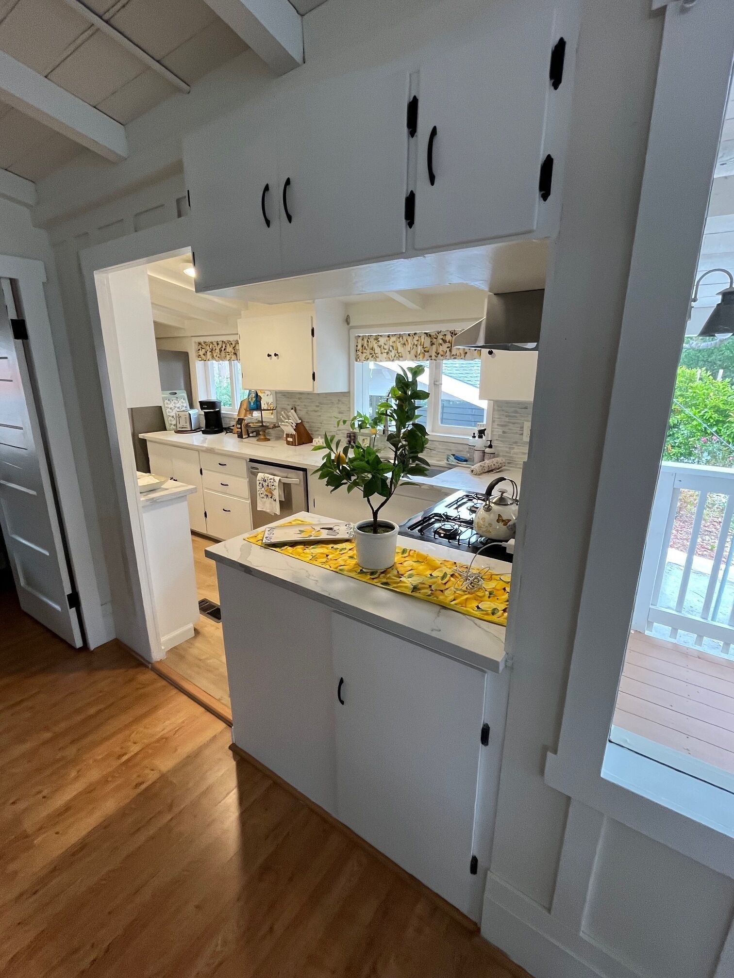 Una cocina moderna con armarios blancos, una isla central y vistas a la terraza exterior.