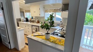 A modern kitchen with white cabinetry, a central island, and a view of the outdoor deck.