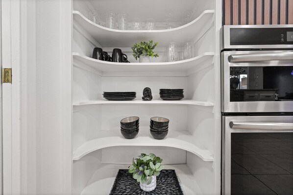 A kitchen with white cabinetry, a built-in oven, and a countertop with a potted plant.