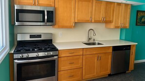 A kitchen with wooden cabinets, a stainless steel microwave, a gas stove, a sink, and a dishwasher.