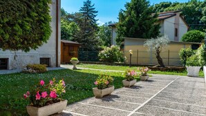 Un patio con un sendero empedrado, plantas en macetas y un edificio con techo inclinado.