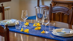 Una mesa de comedor preparada con platos, vasos y una jarrón, decorada con flores amarillas.