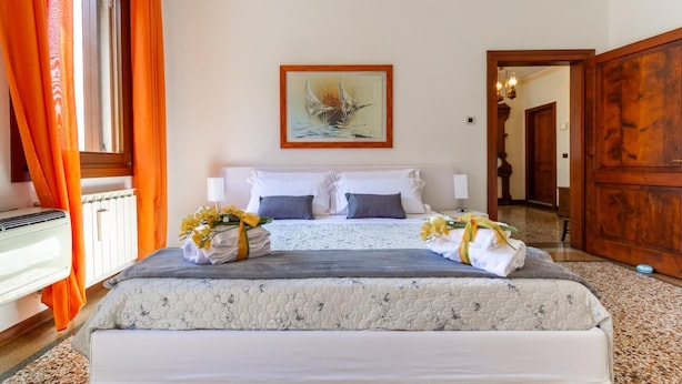 Una habitación de hotel con cama, un radiador, un cuadro en la pared y una puerta de madera.