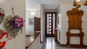 Un pasillo con un armario de madera, una puerta con paneles de vidrio y un aplique de pared.