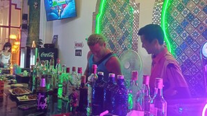 Eine Bar mit einer Auswahl an Flaschen, einem Fernsehbildschirm und dekorativen Wandmustern.
