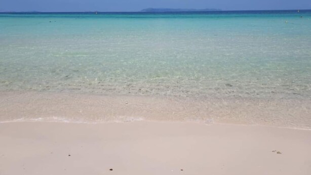 A beach with clear turquoise water and a sandy shore.