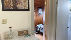 A hallway with a wooden door, a marble countertop with a vintage-style cabinet, a clock, and a framed picture on the wall.
