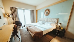A hotel room with two beds, a desk, a chair, a nightstand, and a large mirror on the wall. - Barceló León Conde Luna (León)