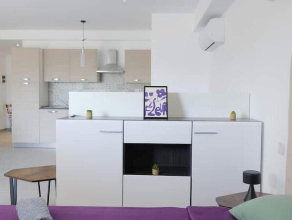 Een moderne keuken met witte kasten, een inbouwfornuis en een hangende lamp.