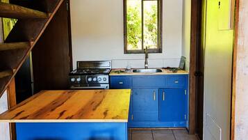 Een keuken met een houten kookeiland, blauwe kastjes, een fornuis en twee barkrukken.