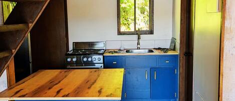 Una cocina con isla de madera, armarios azules, estufa y dos taburetes.