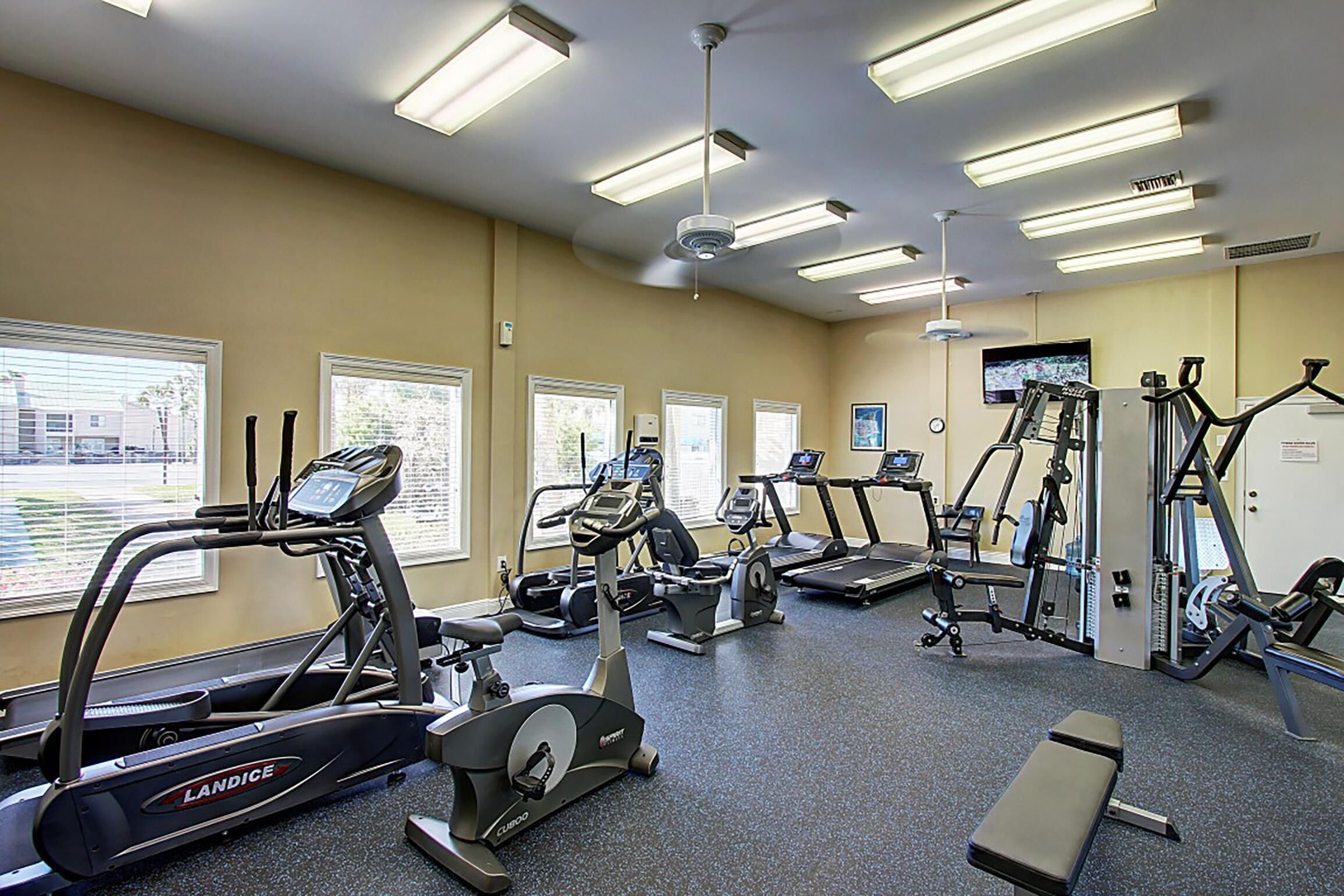 Une salle de sport équipée de tapis de course, de vélos elliptiques et de matériel de musculation.