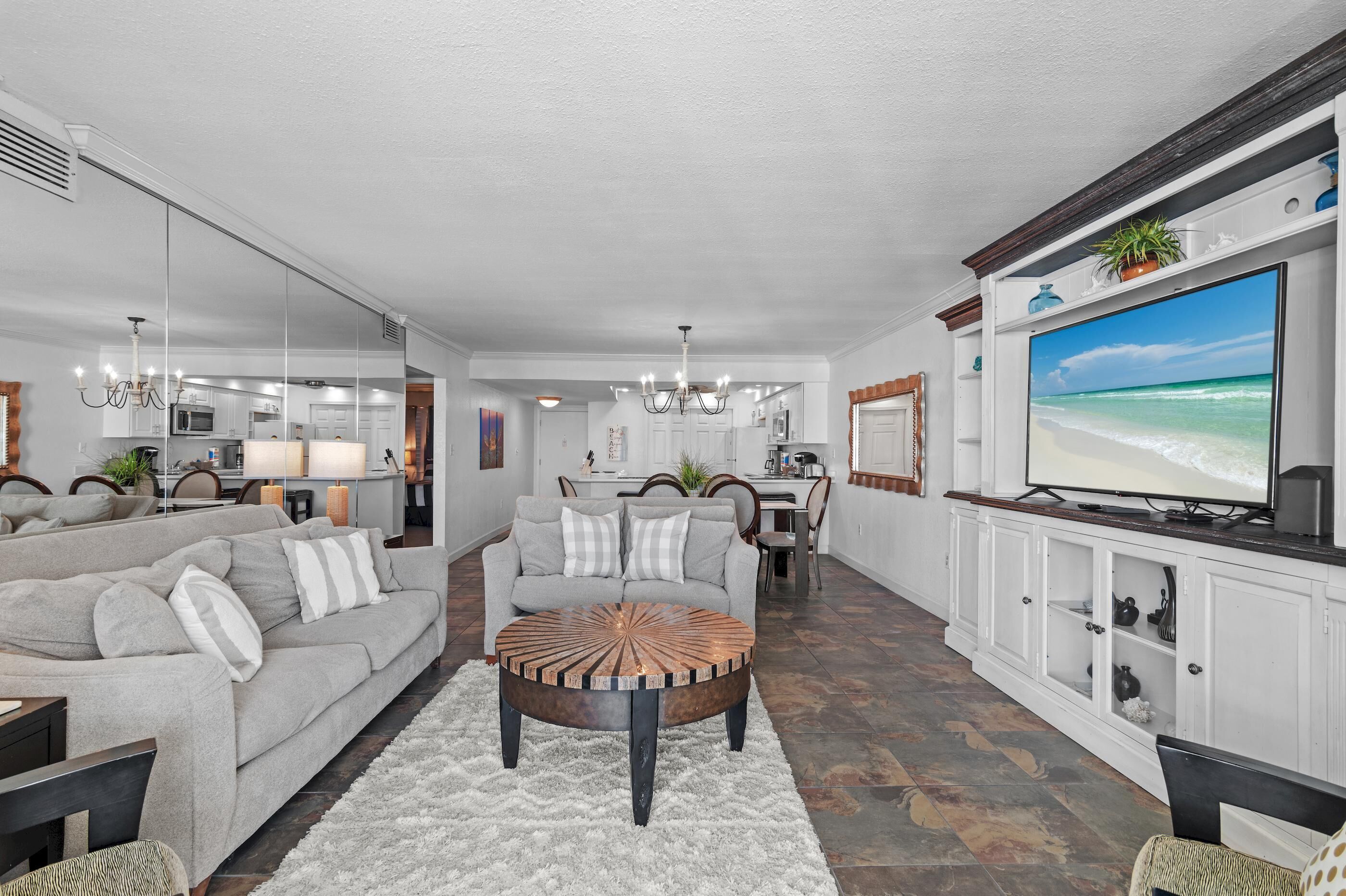A modern living room with a grey sofa, a round coffee table, and a TV on a white cabinet.