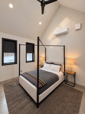 A modern bedroom with a four-poster bed, two bedside lamps, and a ceiling fan. - Hust Haus | Sweeping Catskills Views on 20 Acres (Jeffersonville)