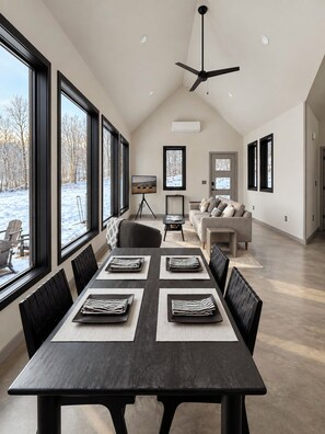 A spacious dining area with a long table, black chairs, and a ceiling fan. - Hust Haus | Sweeping Catskills Views on 20 Acres (Jeffersonville)