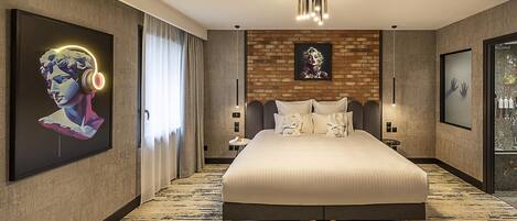 Una habitación de hotel moderna con una cama grande, un muro decorativo de ladrillo y obras de arte en las paredes.