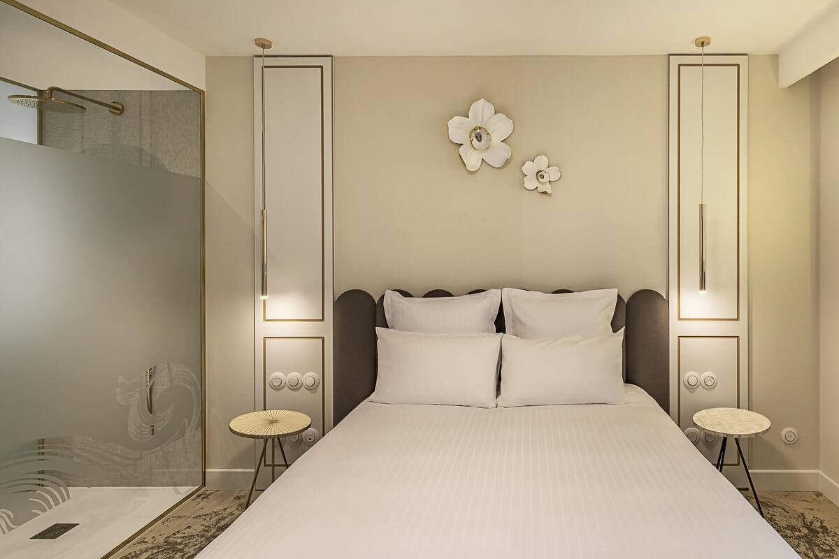 A modern hotel room with a large bed, a shower, and a wall-mounted artwork.