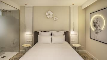 Una habitación de hotel moderna con una cama grande, ducha y una obra de arte en la pared.