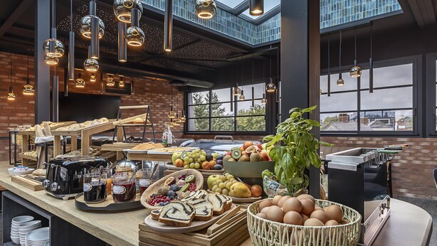 A breakfast buffet with various food items, a coffee machine, and hanging pendant lights in a modern kitchen setting. - Best Western Plus Hotel Saint-Roch Orleans (Orleans)