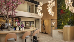 A modern bar area with a curved counter, bar stools, a decorative tree, and a wall-mounted orchid display. - Best Western Plus Hotel Saint-Roch Orleans (Orleans)