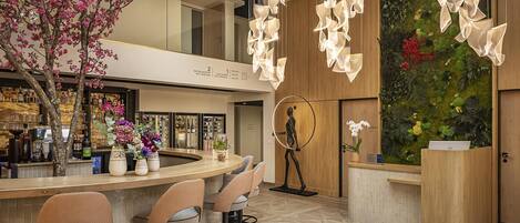 Un área de bar moderna con una barra curva, asientos y una pared decorativa con plantas.